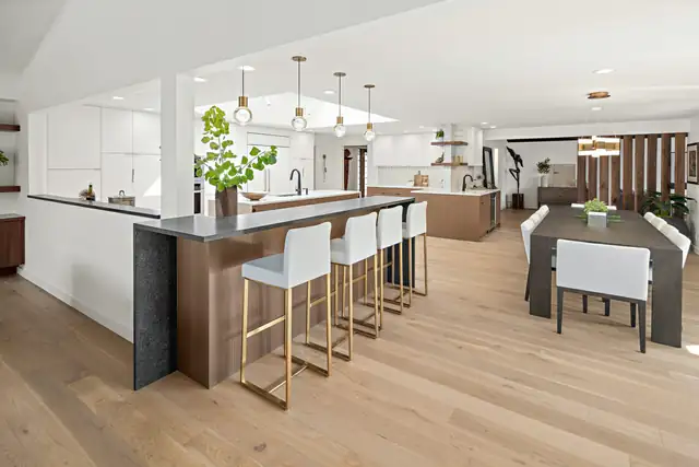 Open-concept kitchen and dining area from a Woodinville full house remodel with a wood-wrapped island and brass pendants