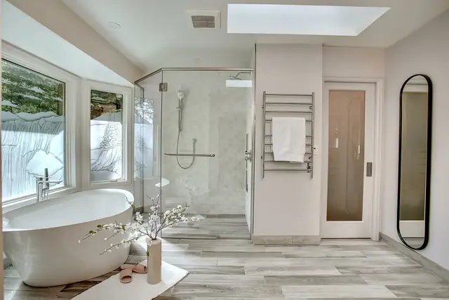 Primary bathroom remodel with a freestanding tub, glass walk-in shower, skylight and heated towel rack