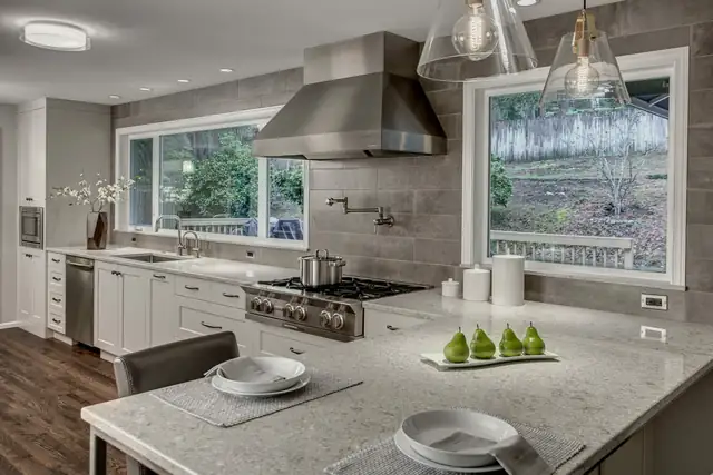 Bridle Trails kitchen remodel with a stainless hood, pot filler, gray tile wall and white shaker cabinets