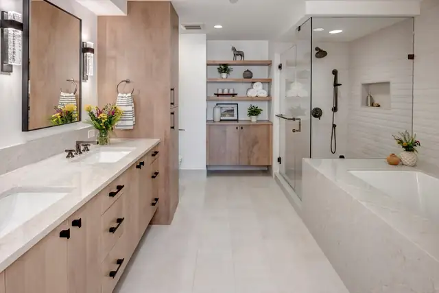 Kirkland condo bathroom remodel with a light wood vanity, quartz-clad tub and glass shower with black fixtures