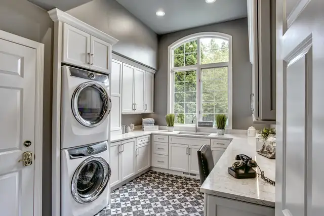 Sammamish laundry room remodel with stacked washer and dryer, white cabinets and patterned cement tile floor